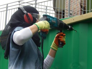 Girl power: fixing a batten for trellis on green hut